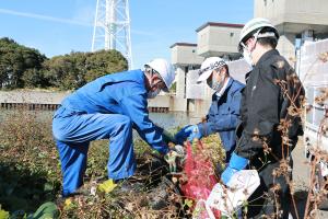 土手に廃棄されたゴミを拾う平田支部長（左）
